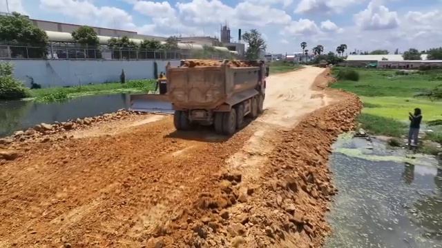 Строительство новой дороги в подкачиваемой воде бульдозером SHANTUI, 25-тонный грузовик сбрасывает г