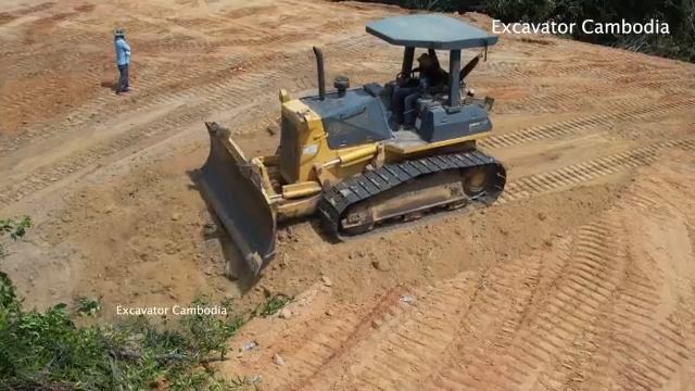 строит дороги с водным самосвалом и бульдозером, толкающим и разгружающим грязь